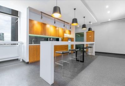 Contemporary office kitchen and break area with a long white breakfast bar.