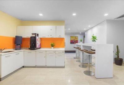 Modern breakroom kitchen with white cabinetry and a bright orange backsplash.