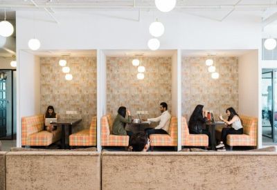 Bright workspace featuring private cushioned seating booths with floral wallpaper.