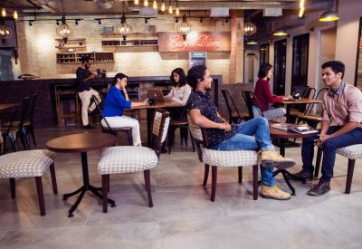 Lively café area with people sitting at round tables and a bar counter.