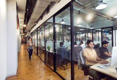 Glass-walled private office corridor with people working at desks.