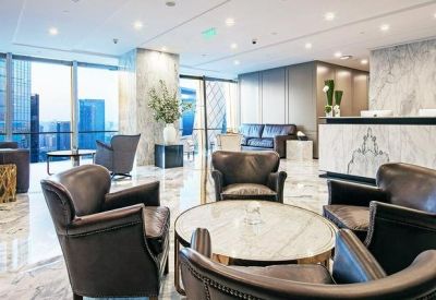 Spacious reception area with marble flooring, leather armchairs, and a large white desk.