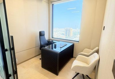 Private office with a black desk, ergonomic chair, and city views through a large window.