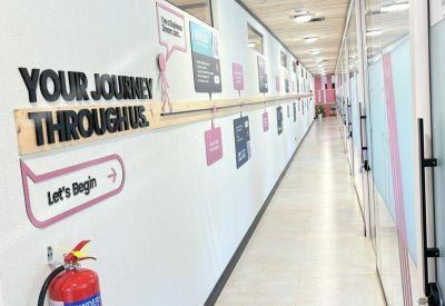 Long corridor with glass-walled offices and motivational wall text.