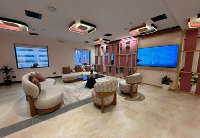 Spacious lounge area with curved sofas, colorful wall panels, and large TV screen.