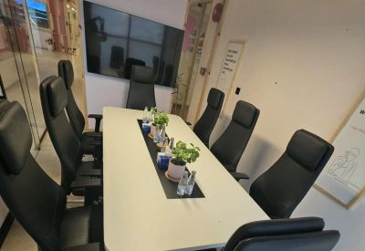 Conference room with a long white table and black leather chairs.