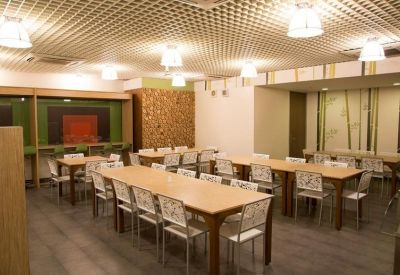 Spacious communal dining area with long wooden tables and patterned chairs.