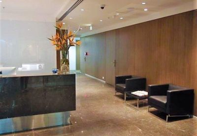 Sleek marble reception desk with black panelling and a waiting area with leather armchairs.
