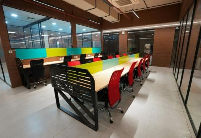 Spacious coworking area with long white desks and bright red office chairs.