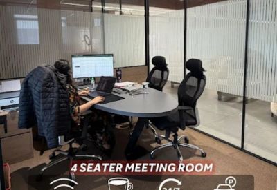 Meeting room for four with a round grey table and ergonomic chairs.