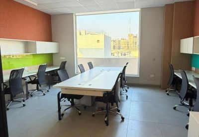 Open plan workspace with multiple white desks and large windows for natural light.