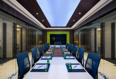 Formal boardroom with a long white table, blue chairs, and integrated ceiling lighting.