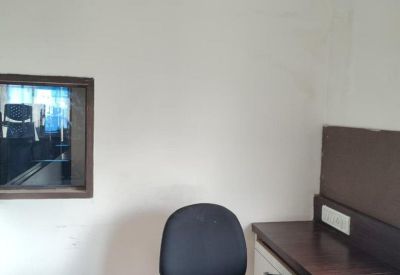 Close-up of a wooden executive desk and black office chair in a bright room.