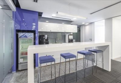 Kitchenette and breakout area with high white bar table and blue stools.