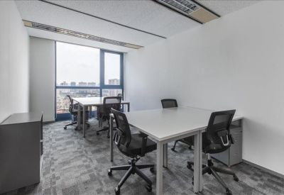 Bright corner office with two white desks and large windows overlooking the city.