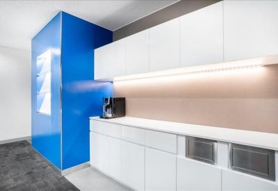 Minimalist kitchen area with white cabinetry and a striking blue feature wall.