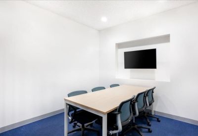 Modern meeting room with a long table and wall-mounted television screen.