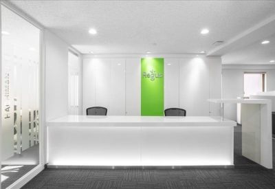 Bright, modern reception area with a white front desk and vibrant green feature wall.