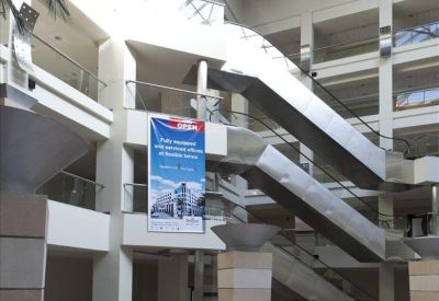 Spacious multi-story atrium with escalators and a glass ceiling.