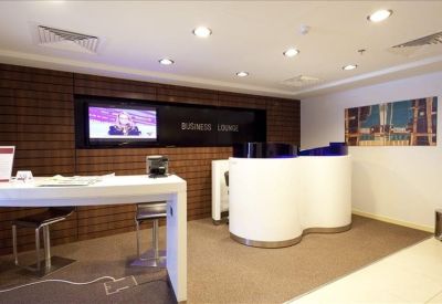 Sleek business lounge with a curved white counter and wall-mounted screen.