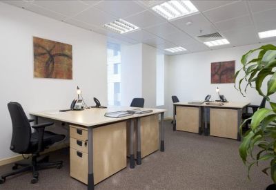 Shared office space with multiple workstations and indoor greenery.
