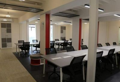 Large coworking area with multiple rows of workstations and red structural pillars.