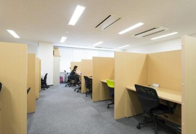 Open-plan workspace featuring private individual desks separated by light wood partitions.