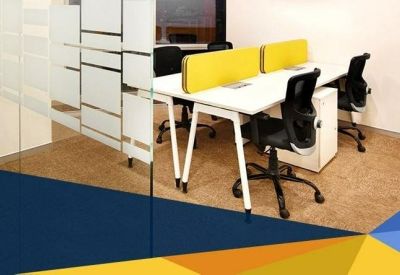 Bright coworking area with white desks, yellow privacy screens, and ergonomic black chairs.