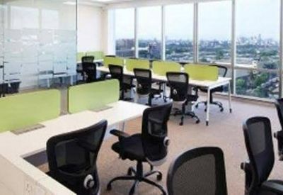 Sun-drenched open-plan office with rows of desks, lime green dividers, and large windows overlooking the city.