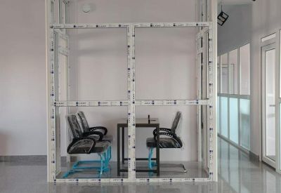 Private office space enclosed in a glass and white frame partition with a desk and chairs.