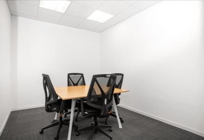 Small meeting room with a wooden table and four black mesh chairs.
