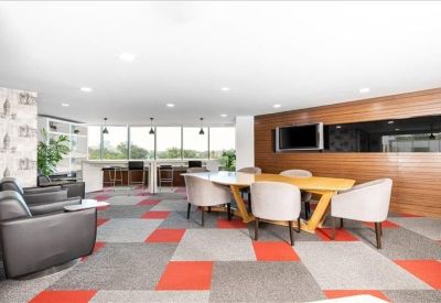 Modern lounge area with colourful patterned carpet, lounge chairs, and wooden wall panels.