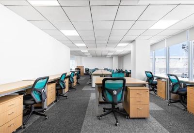 Open-plan office with rows of wooden desks and teal mesh chairs.