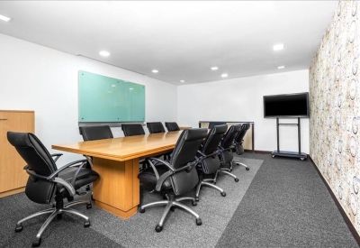 Spacious boardroom with a large wooden table, black leather chairs, and a screen.