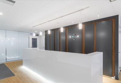 Modern white reception desk with integrated lighting and a dark paneled feature wall.
