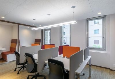 Open-plan coworking area featuring desks with orange privacy screens and ergonomic chairs.