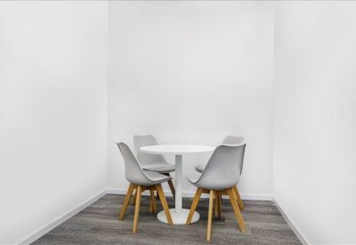 Small breakout area with a round white table and four grey chairs.