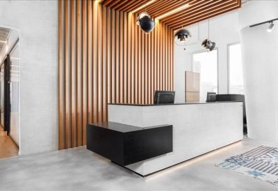 Modern reception desk with a white front and black countertop against a wood-slat feature wall.