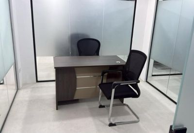 Private office suite with a dark wood desk and glass walls.