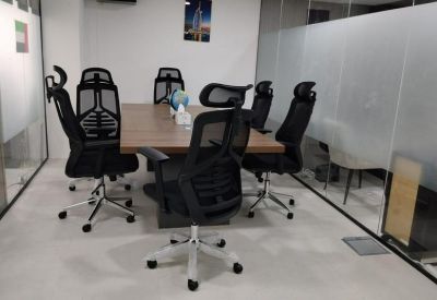 Conference room featuring a wooden table and ergonomic black mesh chairs.