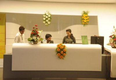 Modern reception desk with white curved counter and colorful floral arrangements.
