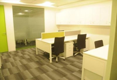 Bright open-plan office space with white desks and black ergonomic chairs.