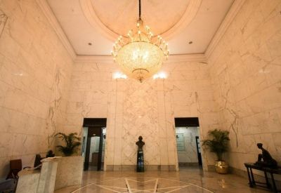 Grand marble lobby featuring a large crystal chandelier, a reception desk, and decorative statues.
