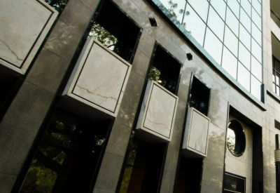 Modern stone building entrance featuring decorative rectangular panels and circular windows.