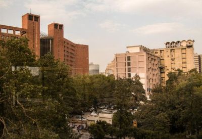 Distant view of red brick and concrete urban office buildings framed by lush green trees.