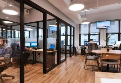 Open-plan office space featuring glass-walled private booths and wooden floors.