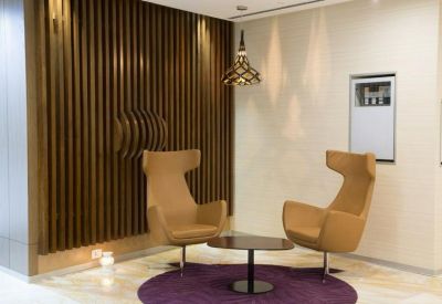 Waiting area with tan wingback chairs and a purple rug against a slatted wood wall.