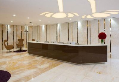 Sleek brown reception desk with marble floors and modern petal-shaped ceiling lights.