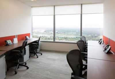Shared office space with rows of desks and large windows overlooking the city.