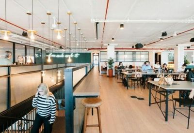 Modern open-plan office with wooden flooring and rows of desks.